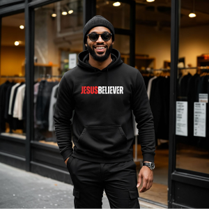 Man wearing a black hoodie with 'Jesus Believer' text, standing in front of a store.